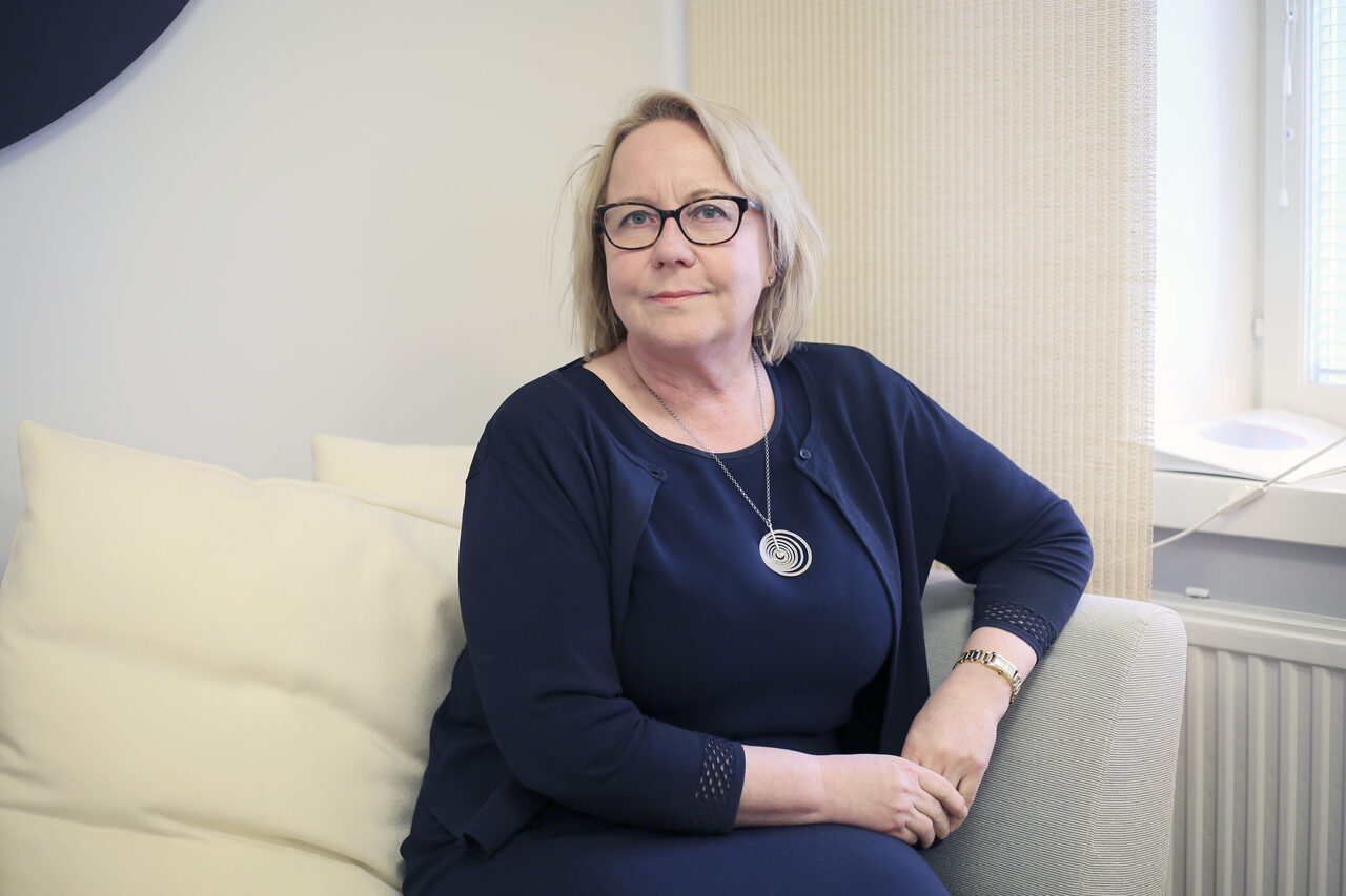 Riitta Kaivosoja istuu sohvalla ja katsoo kameraan.