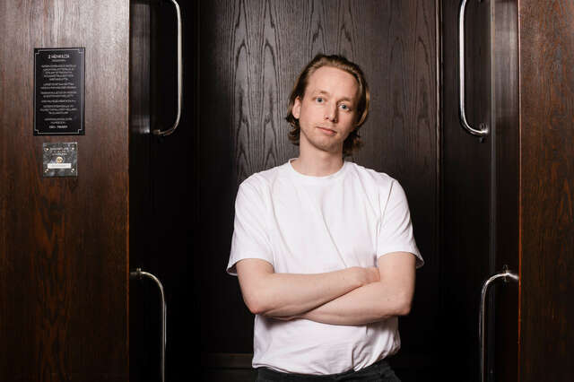 Kuvassa mies, joka katsoo kameraan. Hänellä on valkoinen t-paita.