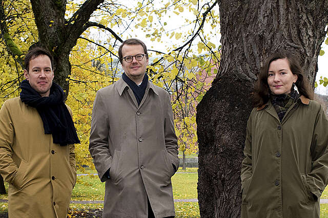 Kuraattorit korkeiden puiden edessä syksyisessä puistossa.