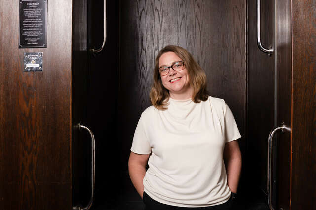 Kuvassa nainen, joka katsoo kameraan. Hänellä on valkoinen t-paita.