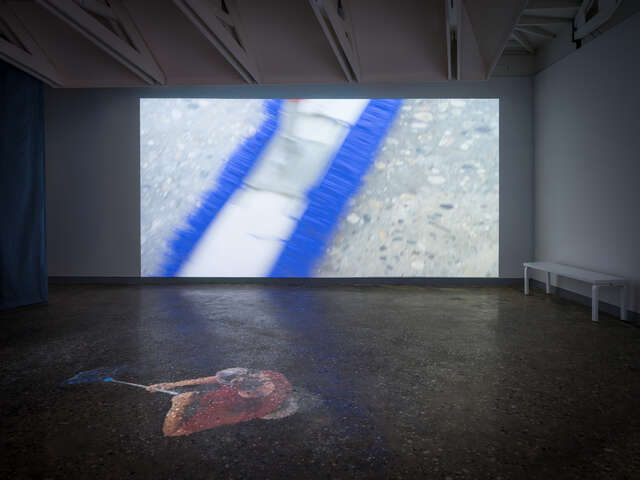 A dark exhibition space with a large image projected in the center.