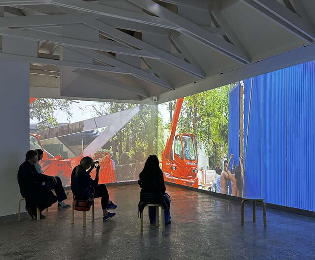 Four people sitting in a space watching wall-sized video projections