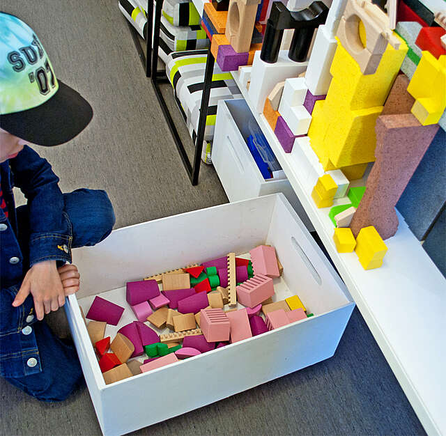 Lapsi tarkastelee valkoista laatikkoa, jossa on värikkäitä legoja.