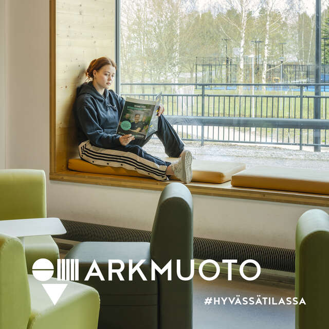 Nuori nainen istuu ikkunasyvennyksessä, etualalla vihreitä nojatuoleja