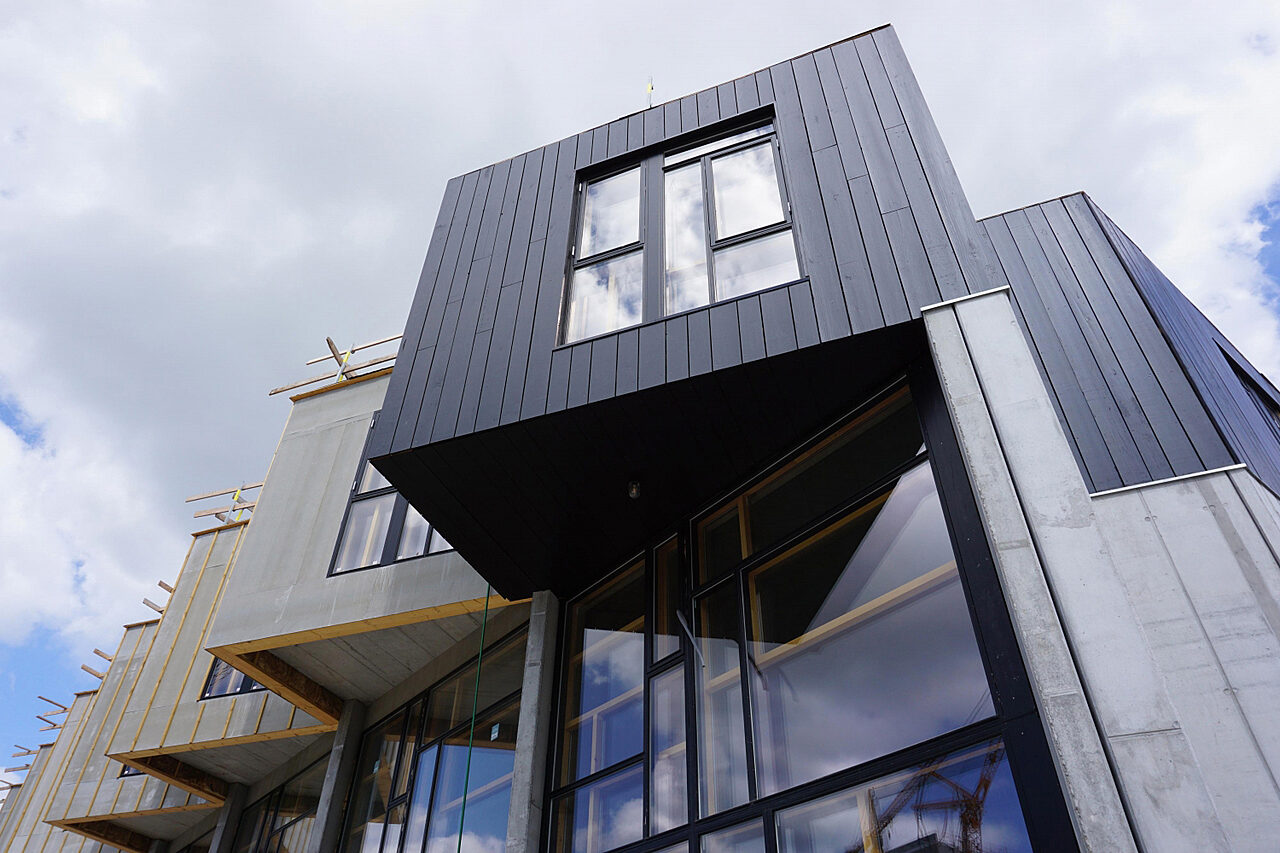 Näkymä rakennuksen julkisivusta. Osa julkisivusta on väriltään tummaa ja osan rakentaminen on kesken.