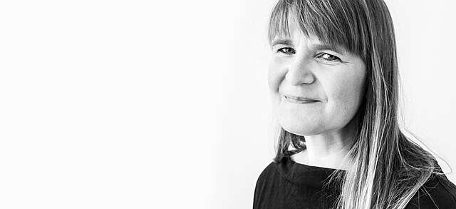 Mustavalkoinen kuva hymyilevästä naisesta