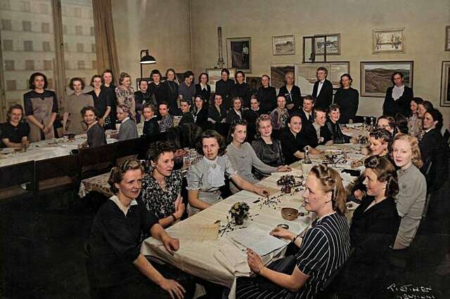 An old photograph of a group of women celebrating and sitting by tables.