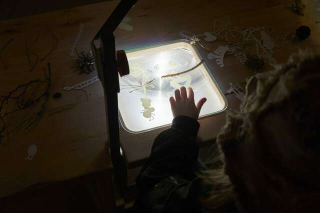 The child's hand touches the light box.