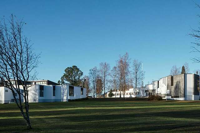 Two modern buildings blending in with the scenery during sunny weather.