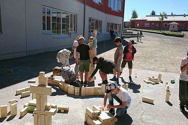 Arkkitehtuurikerhon pihatyöpaja, jossa nuoret lapset kokoavat erikoikosista puupalikoista rakennelmia kesäisessä säässä.