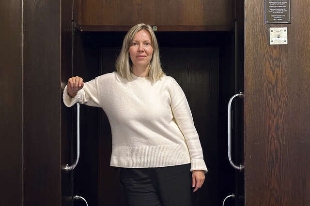 Kuvassa on nainen, jolla on valkoinen paita ja joka katsoo suoraan kameraan.