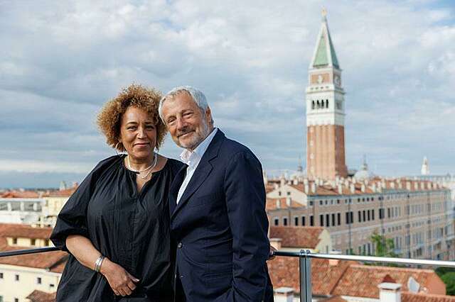 Woman and man in the foreground, urban landscape and church tower in the background.
