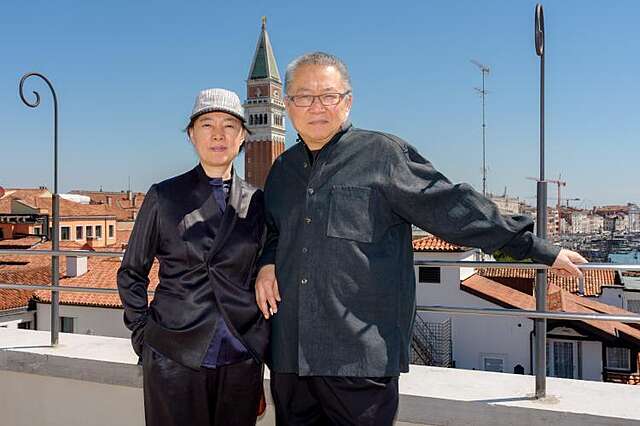 Näyttelyn kuraattorit Wang Shu ja Lu Wenyu hymyilevät kameraan, takanaan Venetsian kaupungin katot.