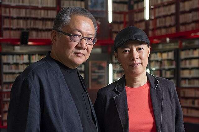 Aasialaisen näköinen mies ja nainen, taustalla kirjahyllyjä