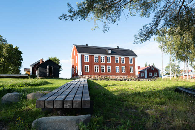 Red wooden mansion building in the centre of a field