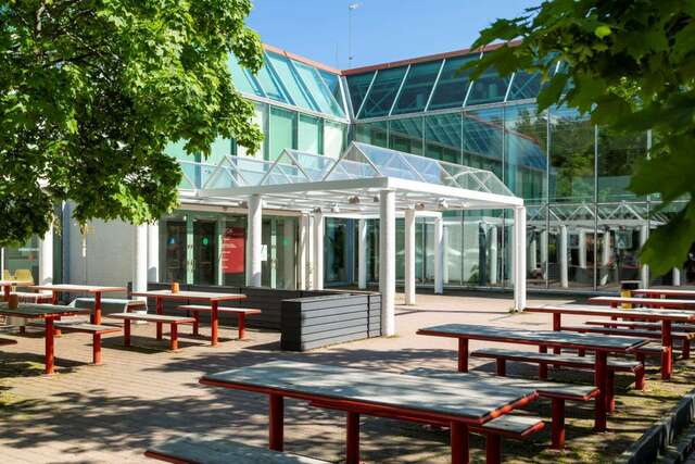 Terrace, tables and benches in front of a building.
