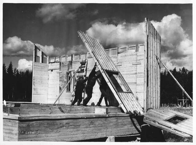 Old photo of people building a wooden house.