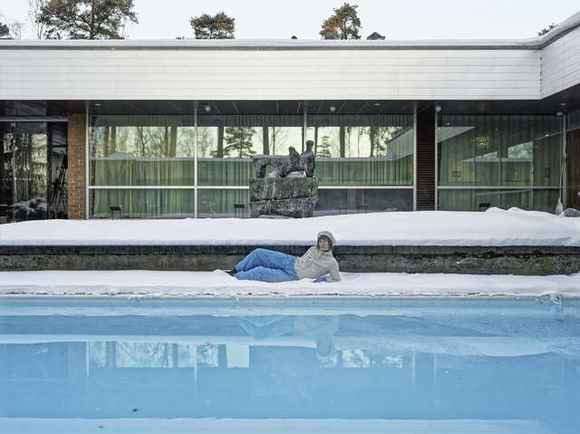 A person is lying in front of a swimming pool.
